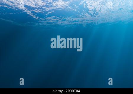 Blue ocean waves from underwater with bubbles. Light rays shining ...