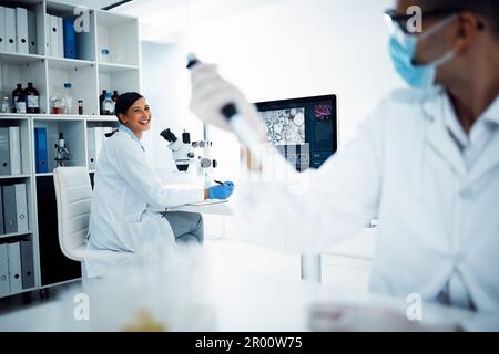 Banter behind the healthcare scenes. two young scientists having a discussion while conducting medical research in a laboratory. Stock Photo