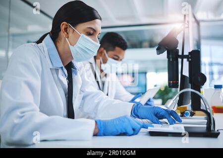 A bit of hard work could make the biggest difference. two young researchers using digital devices in a laboratory. Stock Photo