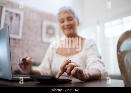 Its never too late to save for a dream. a senior woman using a laptop and calculator while going through finances at home. Stock Photo