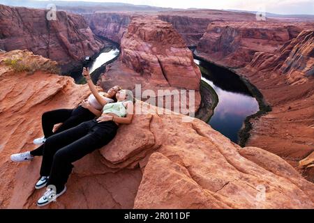 Two young women enjoy the spectacular scenery while taking a selfie at The Horseshoe Bend in Arizona, USA. Stock Photo
