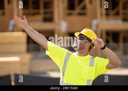 Builder with hardhat helmet on construction site. Construction engineer worker in builder uniform near construction building. Portrait of builder in a Stock Photo