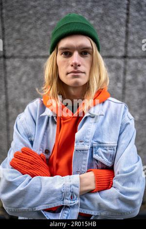 Street portrait of stylish European millennial hipster guy posing against gray concrete wall Stock Photo