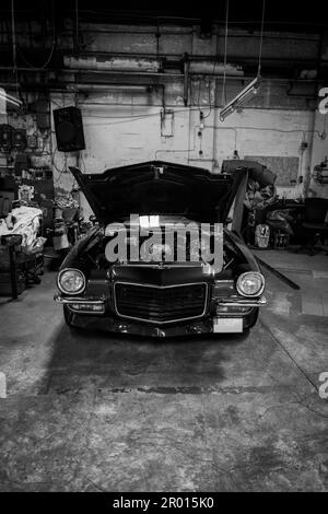 An old cheverolet with open engine hood stands in a workshop Stock Photo