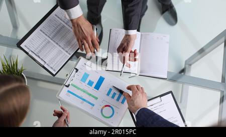 Business team analyzing income charts and graphs. Top view photo shoot. Stock Photo