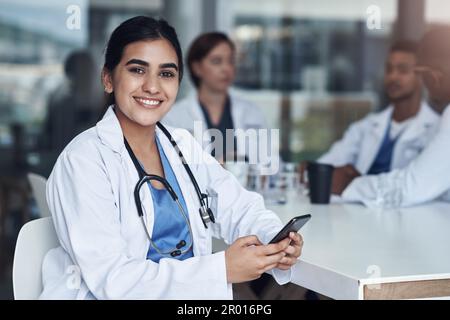 Finally taking a break. a young female doctor using her smartphone to send a text message. Stock Photo