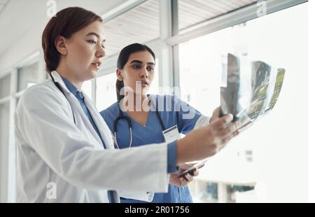 A place where humanity is loved. two young doctors checking exrays in a hospital. Stock Photo