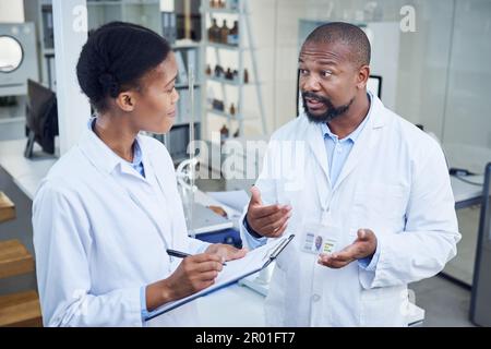Ensuring they have everything under control. two scientists having a discussion in a lab. Stock Photo