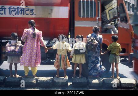 a Women with children like to cross over a road with traffic and People in the city centre of Mumbai in India.  India, Mumbai, March, 1998 Stock Photo