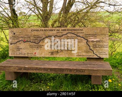 Wooden seat at side of Monmouthshire and Brecon Canal at Pencelli Powys Mid Wales UK showing a carved map of part of  canal's route from Brynich Lock Stock Photo