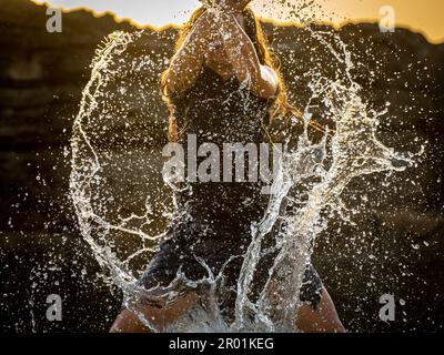 middle-aged woman dancing and throwing water in the air, Maioris beach, llucmajor, Majorca, Balearic Islands, Spain. Stock Photo