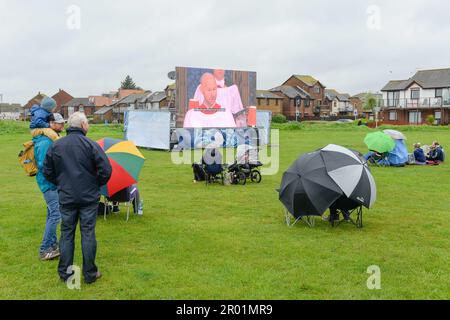 Poole, Dorset, UK.  6th May 2023.  UK Weather.  Coronation revellers wearing waterproofs and with umbrellas brave the rain to watch the Coronation of King Charles III on a big screen at Baiter Park at Poole in Dorset.  Picture Credit: Graham Hunt/Alamy Live News Stock Photo