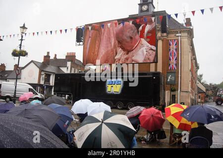 Henley-on-Thames, UK. 6th May, 2023. Spectators brave the rain to watch the Coronation of King Charles III on a big screen in the Marketplace. Credit: Uwe Deffner/Alamy Live News Stock Photo