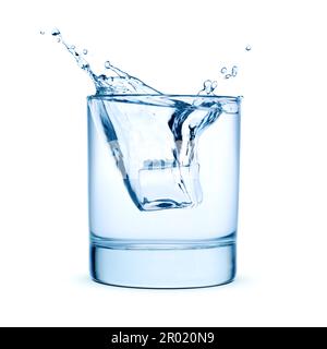 Ice cubes falling into a glass of water with splash, isolated on white background. Stock Photo
