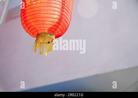 Red Asian lantern made of silk, simple background with copy space. Traditional Chinese fabric lantern on a city street in the light of day Stock Photo