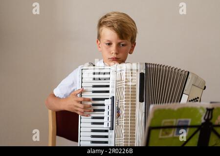 Boy teen focusing on playing an piano accordion, professional accordionist Stock Photo