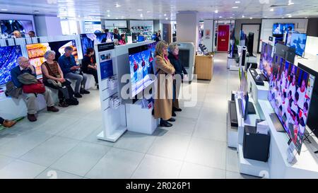 London, UK.  6 May 2023. People watch the coronation of King Charles III and Queen Camilla on large screen TVs at the flagship John Lewis department store in Oxford Street.  This is the UK’s first coronation in 70 years and the first to take place in the digital age.   Credit: Stephen Chung / Alamy Live News Stock Photo
