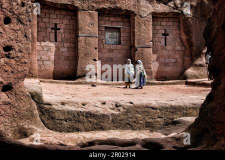 Lalibela, Ethiopia - January 6, 2018: Women walking outside the Biete Qeddus Mercoreus in Lalibela, Ethiopia. Stock Photo