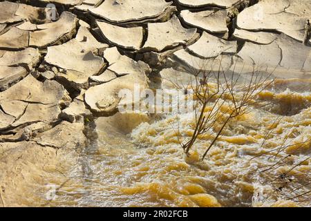 Raging waters and murky after several days of rain versus infertile land burned by the sun - concept image Stock Photo