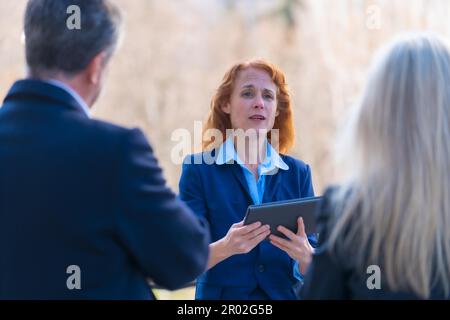 Collaborative and Innovative Red-Haired Female Business Professional Engaging in Teamwork with Colleagues through Digital Tablet while Participating Stock Photo