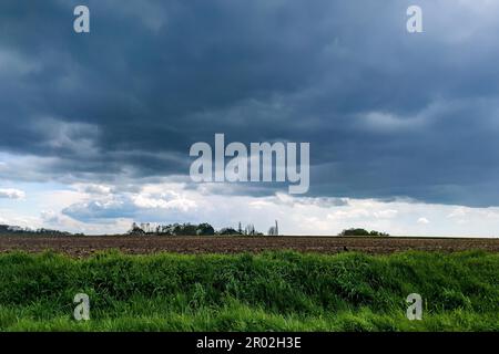 Dark rain clouds hovering over arable land field for agriculture agricultural use, Germany Stock Photo