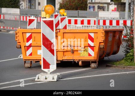 Container, orange skip for building rubble with barrier beacons standing on the road, construction site, road works, Germany Stock Photo