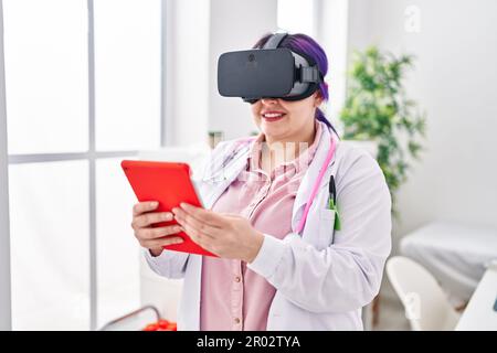 Young beautiful plus size woman doctor using virtual reality glasses at clinic Stock Photo
