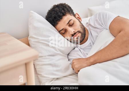 Young arab man lying on bed sleeping at bedroom Stock Photo