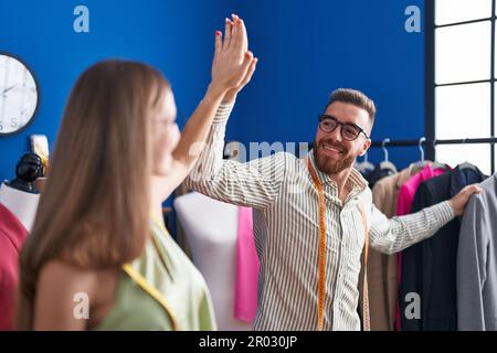 Man and woman tailors high five with hands raised up at clothing factory Stock Photo