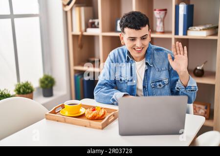 Young non binary man having video call and breakfast at home Stock Photo
