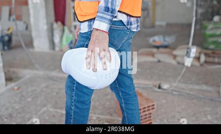 Middle age man builder holding hardhat walking at construction site Stock Photo