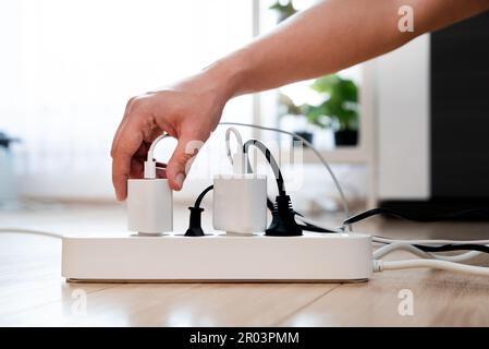 Hand holding electric plug, Multiple socket with connected plugs, energy efficiency Stock Photo