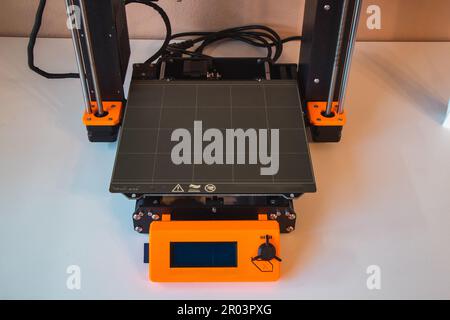Technological hi-teg tool for making new things. A black and red 3D printer at work. The object is created by laying down continuous layers of materia Stock Photo