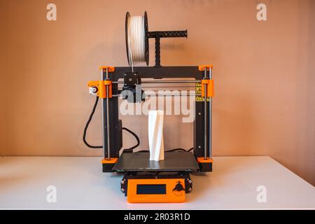 Technological hi-teg tool for making new things. A black and red 3D printer at work. The object is created by laying down continuous layers of materia Stock Photo