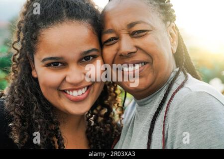 Portrait of happy African mother and daughter having fun outdoor in summer day - Love family concept - Soft focus on senior woman eyes Stock Photo