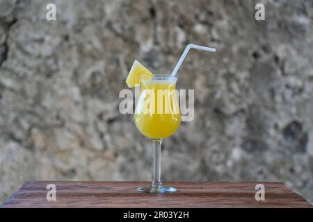 Freshly squeezed juice from pineapple in a glass goblet on the background of an old stone wall. Island of Zanzibar, Tanzania, East Africa. Close up, c Stock Photo