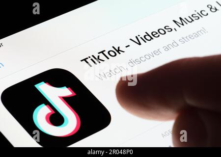 TikTok app seen in App Store on the screen of ipad and blurred finger pointing at it. Selective focus. Stafford, United Kingdom, May 6, 2023 Stock Photo