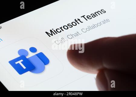 Microsoft Teams app seen in App Store on the screen of ipad and blurred finger pointing at it. Selective focus. Stafford, United Kingdom, May 6, 2023 Stock Photo