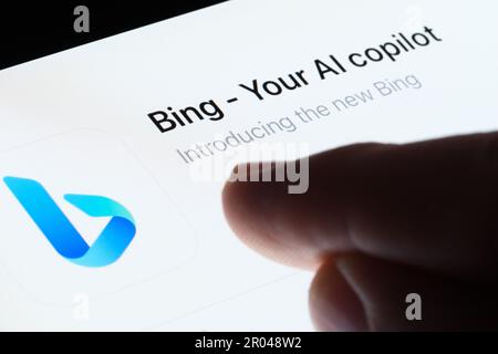 Bing app seen in App Store on the screen of ipad and blurred finger pointing at it. Selective focus. Stafford, United Kingdom, May 6, 2023 Stock Photo