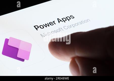 Power Apps icon seen in App Store on the screen of ipad and blurred finger pointing at it. Selective focus. Stafford, United Kingdom, May 6, 2023 Stock Photo