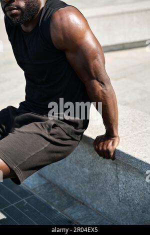 Fit young African man wearing black sportswear training in urban park. Stock Photo