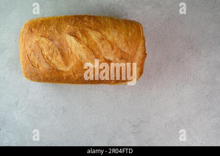 Savour the taste of freshly baked bread with this artisanal white rustic loaf. Baked to perfection, the oval-shaped loaf boasts a crispy and crusty ext. Stock Photo