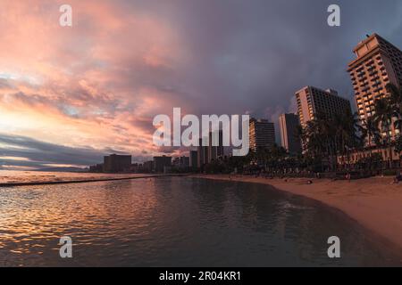 Capture the beauty of Hawaii's famous Waikiki Beach at sunset with this digital photo. This stunning image features the golden glow of the sun. Stock Photo