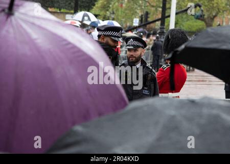 London, UK. 6th May 2023. Police officers stand guard in the rain. Hundreds of thousands of people from all over the world are braving the weather to watch the procession for the coronation of King Charles III and Queen Camilla on Saturday, May 6th, 2023. Credit: Kiki Streitberger / Alamy Live News Stock Photo