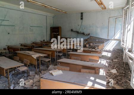 View of interior of classroom with desks and books on student's desks in school in abandoned city of Pripyat in Ukraine on May 6, 2023 from where all dwellers were evacuated after disaster on Chernobyl nuclear plant Stock Photo