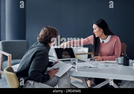 Shes got an eye for detail and design. two young architects going over designs on a laptop together in their office. Stock Photo