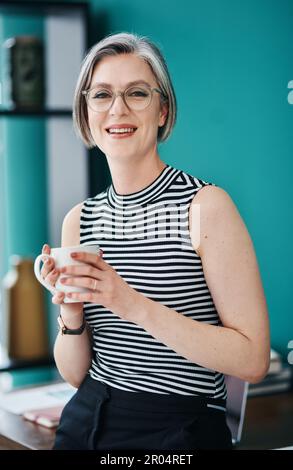 Success is on the other side of fear. a mature businesswoman having coffee in her office. Stock Photo