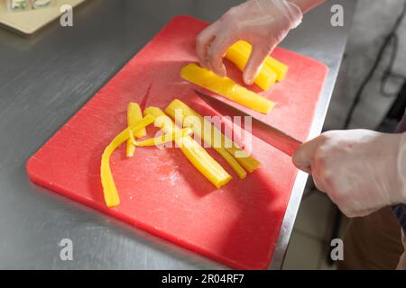The cook cuts pickled daikon for sushi on a red board. High quality photo Stock Photo