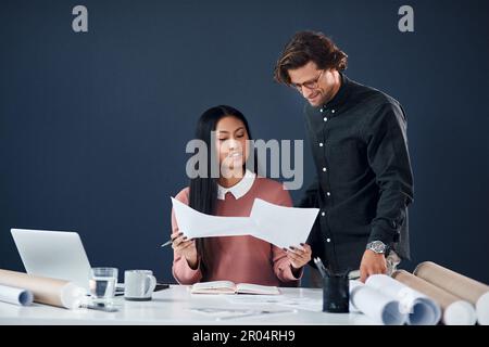 Weve got our hands full today. two young architects going over building plans and paperwork together in their office. Stock Photo