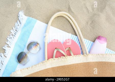 Striped towel with beach accessories on sand, flat lay Stock Photo